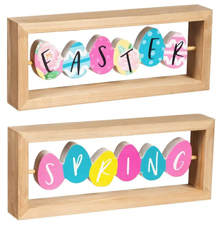 A rectangular wooden tabletop decoration made up of brightly colored eggs. One side reads EASTER and one side reads SPRING