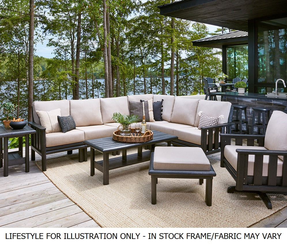 A cushioned patio furniture set on a porch next to a house in the woods