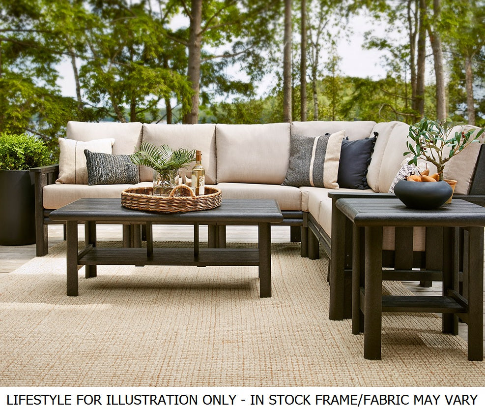 A cushioned patio sectional with a coffee table and an end table on a balcony in the woods