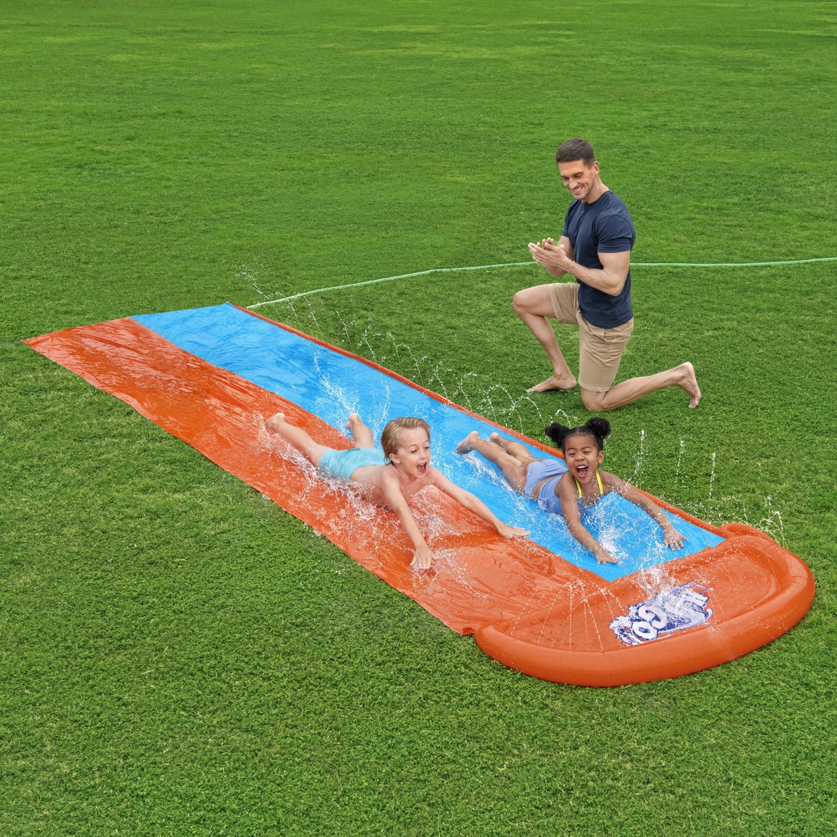 A slip n slide with two lanes that lead into a splash pad.