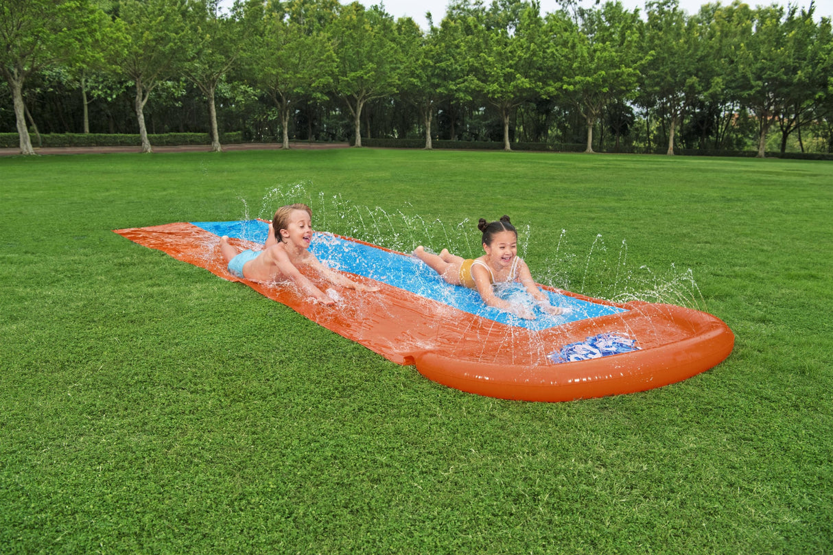 A slip n slide with two lanes that lead into a splash pad.