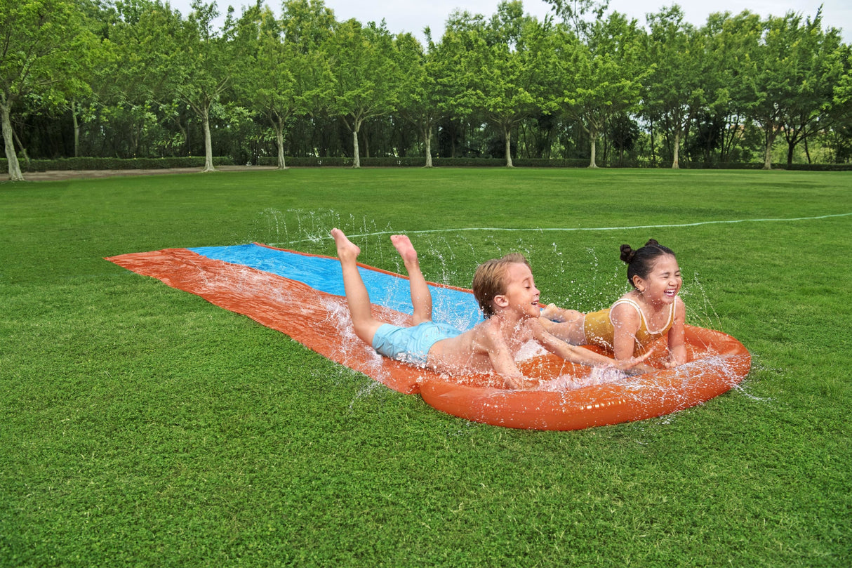 A slip n slide with two lanes that lead into a splash pad.