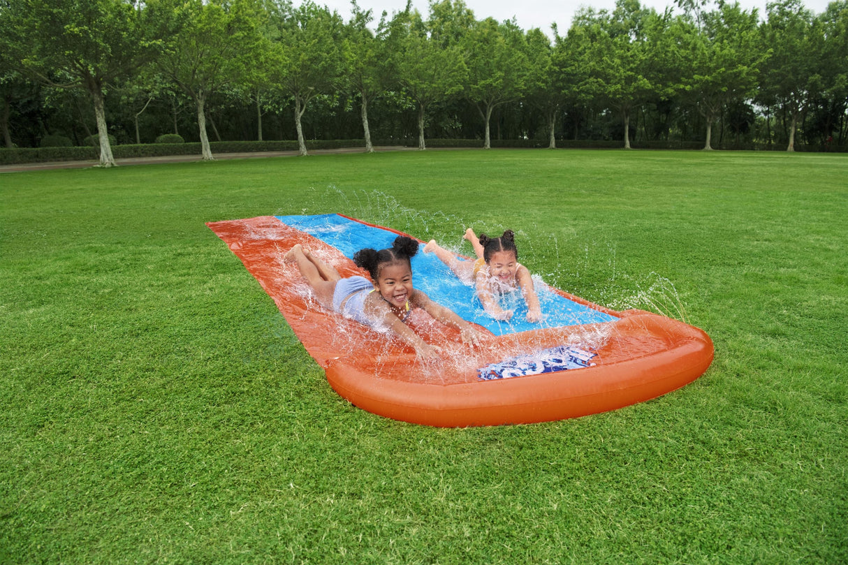 A slip n slide with two lanes that lead into a splash pad.