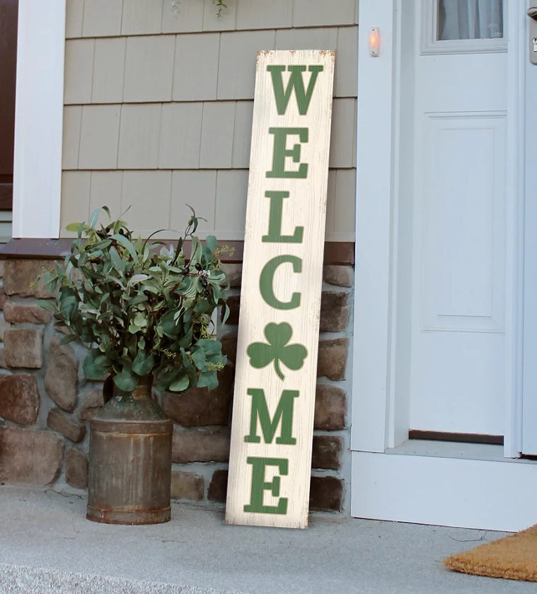 Outdoor porch decoration that reads "WELCOME" in a green font. The O is shaped like a shamrock.