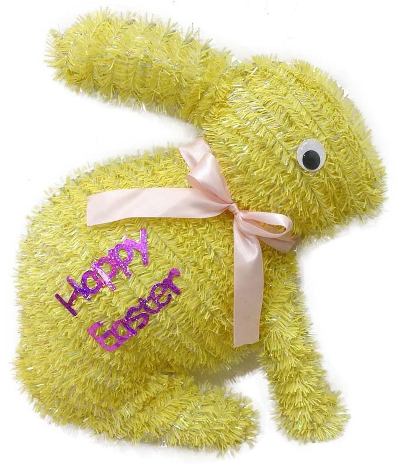 A yellow tinsel tabletop decoration shaped like bunnies that read "HAPPY EASTER" and features a light pink bow around its neck
