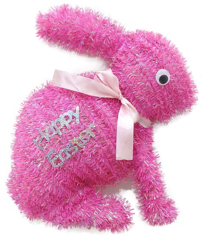 A pink tinsel tabletop decoration shaped like bunnies that read "HAPPY EASTER" and features a light pink bow around its neck
