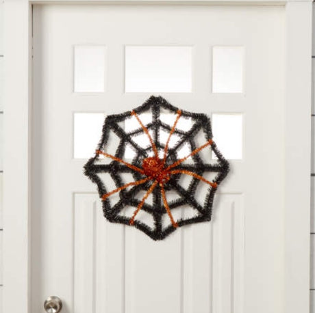 Black tinsel decoration shaped like a web with a spider in the center. One features a purple spider and the other features an orange spider.