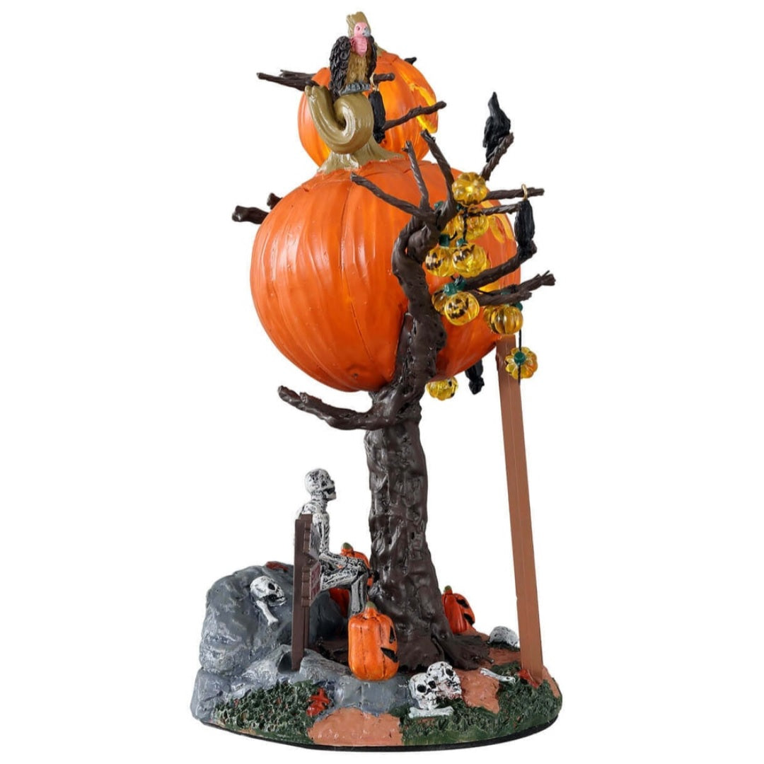 Polyresin village accent for a Lemax display. Designed to look like a treehouse made out of carved pumpkins. There are pumpkin lights, bats and black crows hanging from the branches. There's a vulture on the roof and a ladder leaning against the tree. There's a skeleton sitting underneath the treehouse among skulls, pumpkins and signs reading "BEWARE!" and "ENTER IF YOU DARE!"