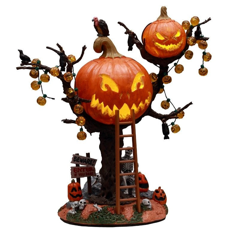 Polyresin village accent for a Lemax display. Designed to look like a treehouse made out of carved pumpkins. There are pumpkin lights, bats and black crows hanging from the branches. There's a vulture on the roof and a ladder leaning against the tree. There's a skeleton sitting underneath the treehouse among skulls, pumpkins and signs reading "BEWARE!" and "ENTER IF YOU DARE!"