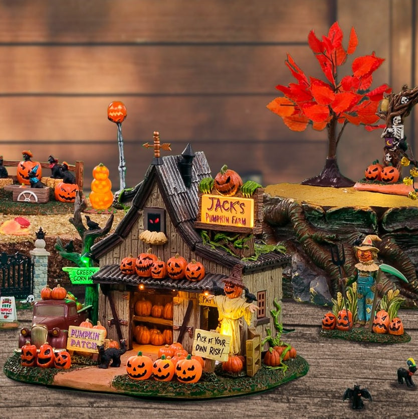 Polyresin building for a Lemax display. Designed to look like a spooky cottage on a pumpkin farm. There's a red truck on the side near a tree with a sign on it that reads "CREEPY CORN MAZE!" There's a scarecrow with crows sitting on it. There's another sign that reads "PICK AT YOUR OWN RISK!"