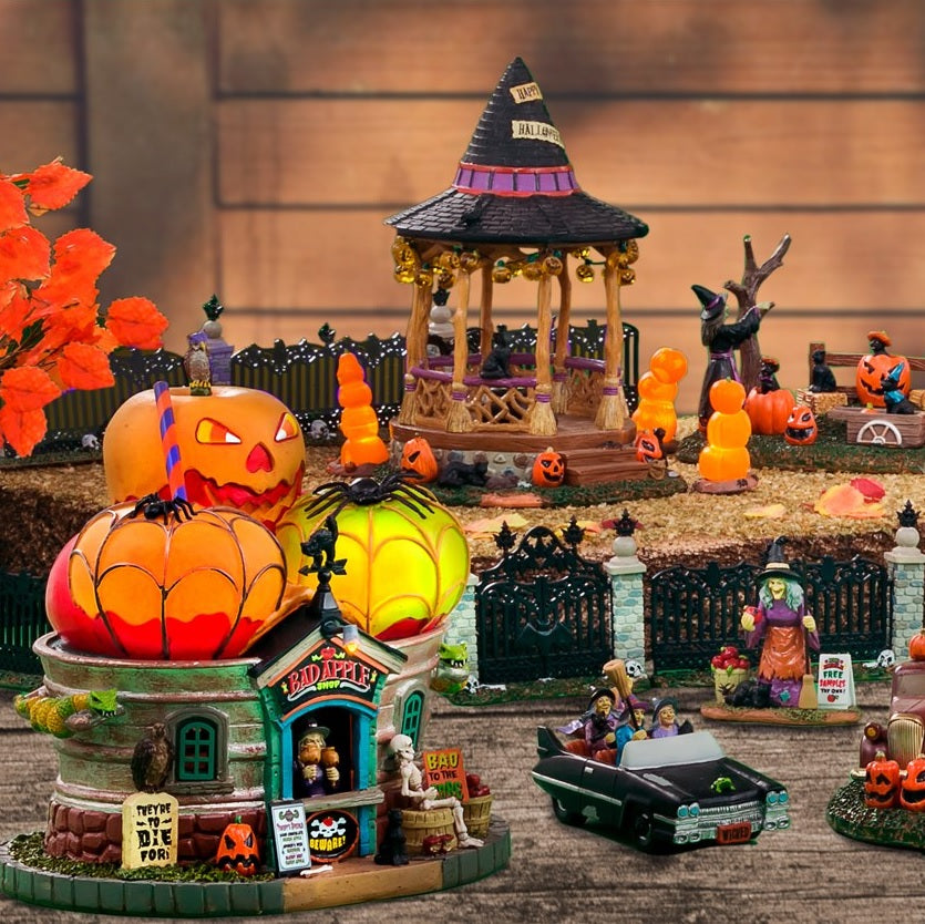 Polyresin building for a Lemax display. Designed to look like a building with a roof made out of giant apples. There's a witch at the front booth handing out caramel covered apples. There are snakes, owls, black cats, tombstones, a skeleton sitting on a barrel and a barrel of apples.