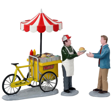 Polyresin figurines for a Lemax Village tabletop display. Designed to look like a taco vendor handing a man a taco from his taco cart