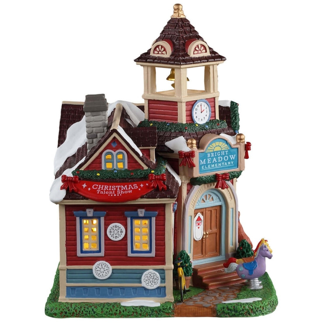 Porcelain lighted building for a Lemax display. Designed to look like a school. There's a bell tower and Christmas garland along the edges of the roof. It reads "Bright Meadow Elementary." There's a dog peeking into a classroom window. There are two spring riders shaped like horses in front of the door. There's a red banner that reads "Christmas Talent Show."