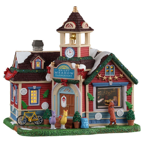 Porcelain lighted building for a Lemax display. Designed to look like a school. There's a bell tower and Christmas garland along the edges of the roof. It reads "Bright Meadow Elementary." There's a dog peeking into a classroom window. There are two spring riders shaped like horses in front of the door.