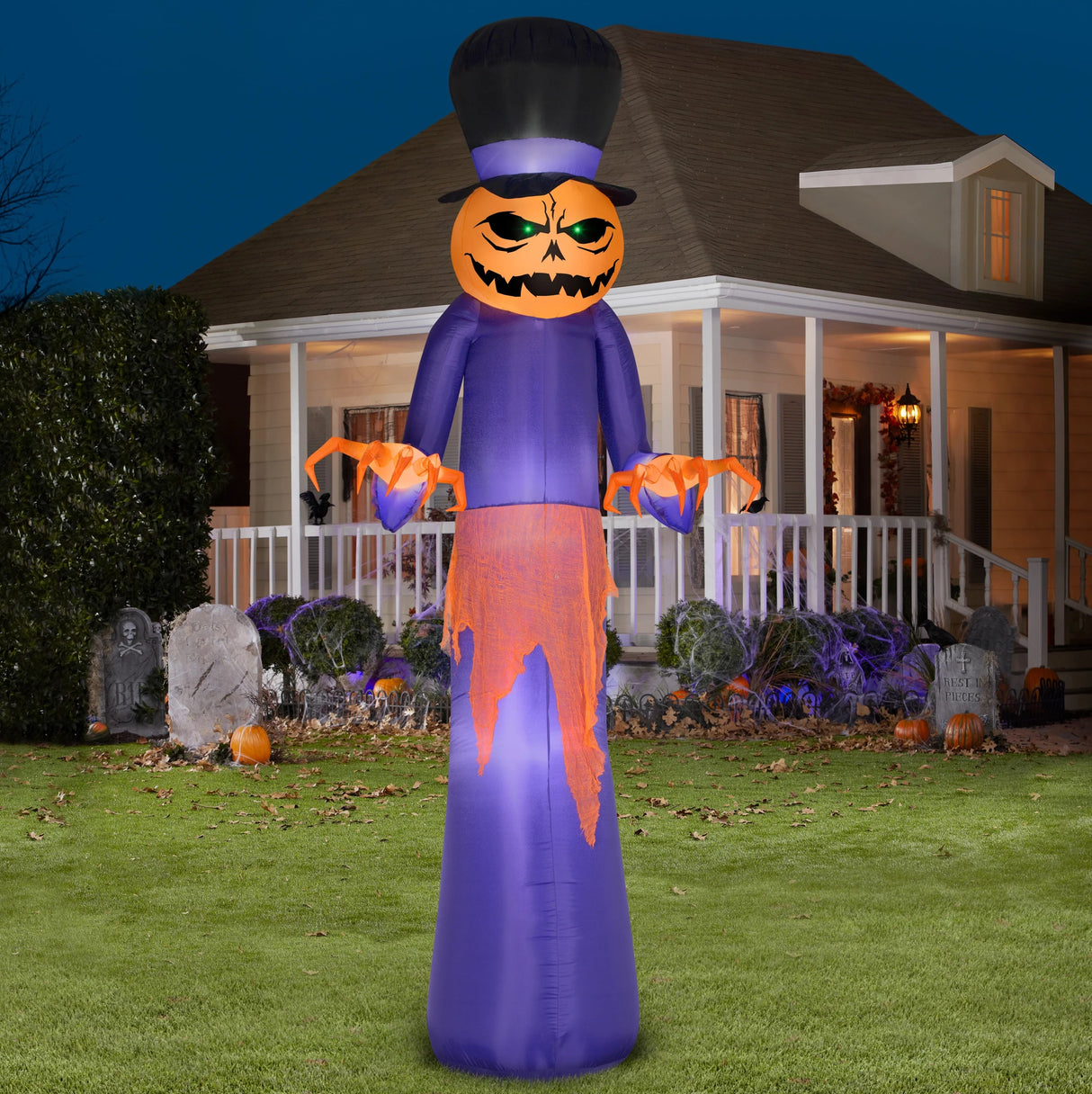 Inflatable decoration shaped like a monster with a scary jack-o-lantern head. He's wearing a black top hat, a purple dress with some orange fabric across the hips.
