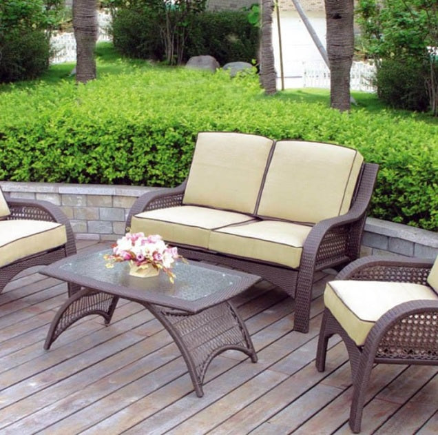 Patio furniture set on a stone patio. The frames are dark brown and the cushions are an orange-ish, tan color.