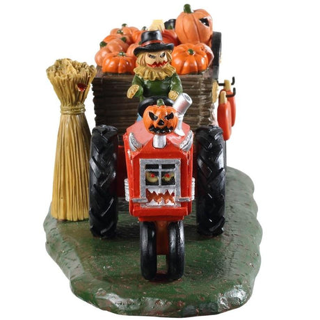 Polyresin village accent for a Lemax display. Designed to look like a scarecrow driving a red tractor with cart attached to it that's full of pumpkins. There's a sign on the side that reads DAYS TO HALLOWEEN and you can change the number.