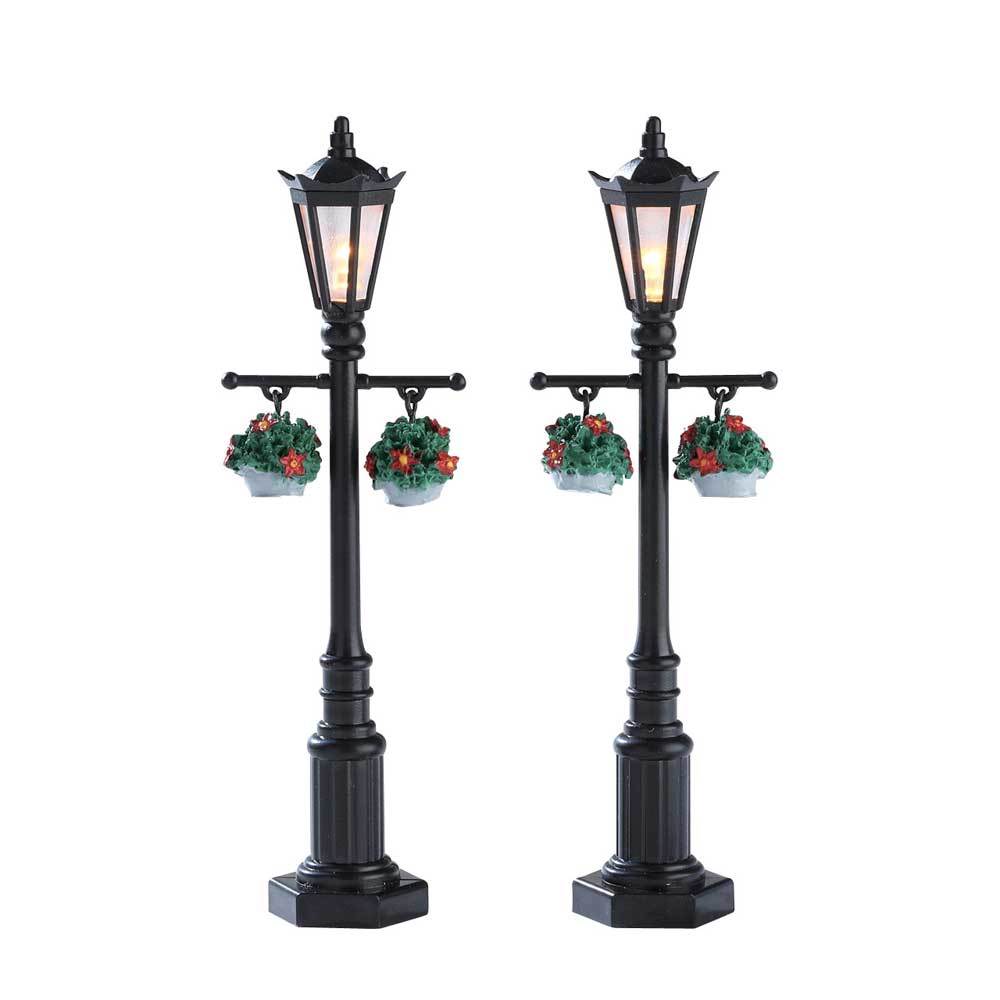 Lemax village accessories designed to look like black lampposts. There are two lampposts in this set. Each lamppost has two hanging potted plants.