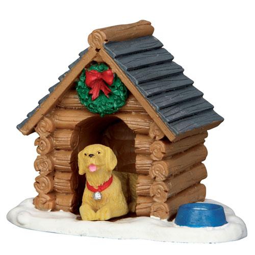 Polyresin figurine for a Lemax display. Designed to look like a log cabin-inspired dog house. There's a wreath with a red ribbon near the roof. There's a blue bowl off to the side and a yellow dog with a red collar inside.
