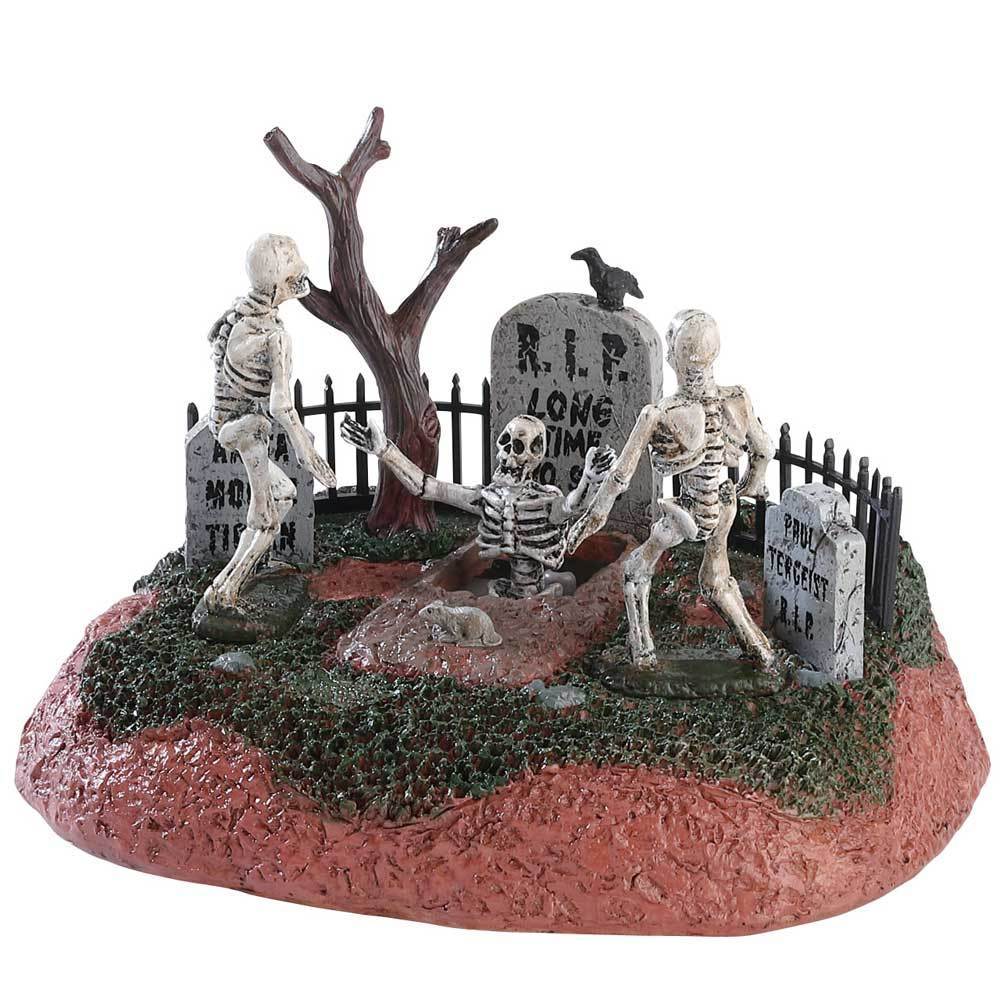 Polyresin table accent for a Lemax display. Designed to look like a graveyard with tombstones and a bare tree. There are two skeletons trying to help another skeleton out of a grave.