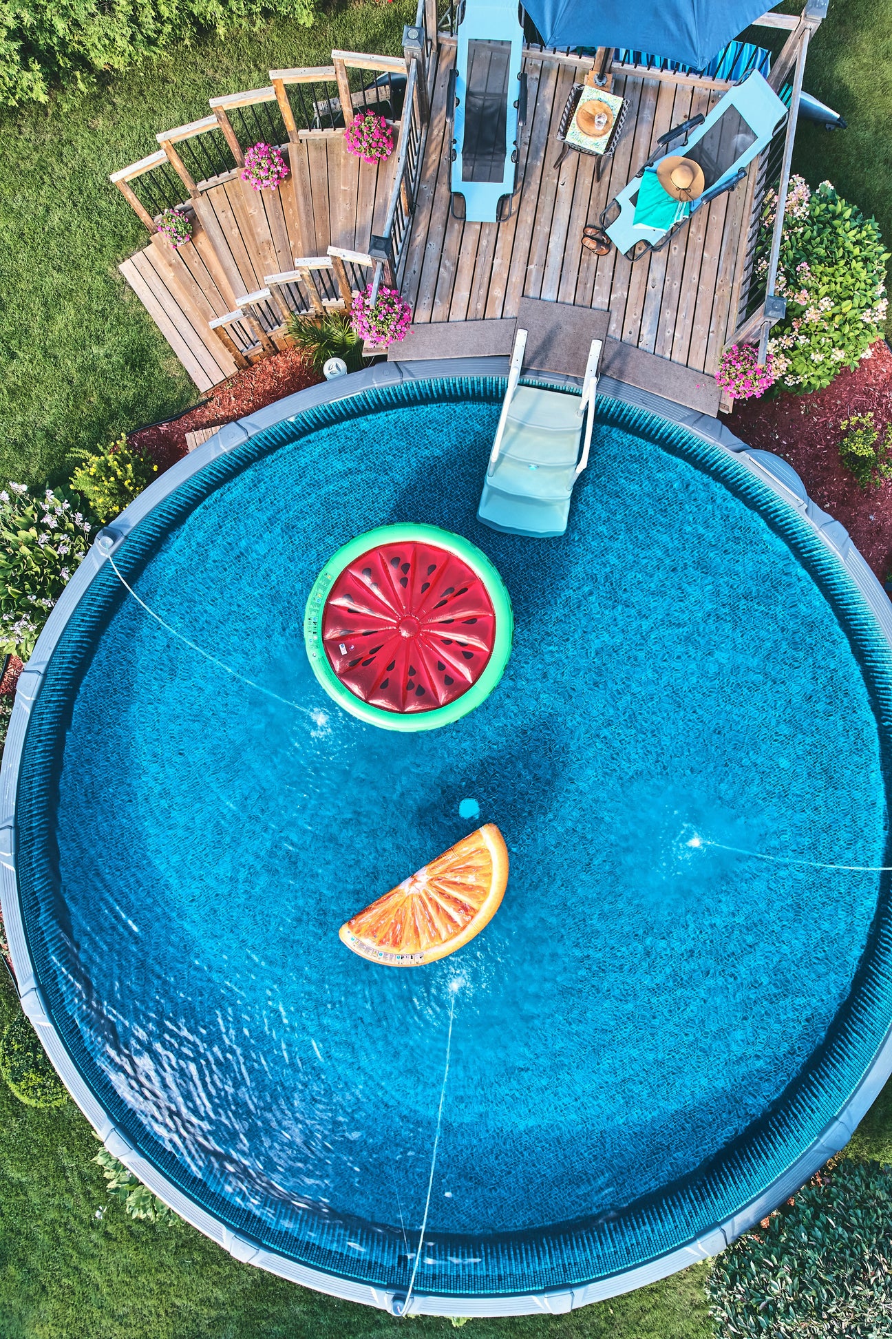 Round above ground swimming pool from above with a watermelon and orange float in the pool.