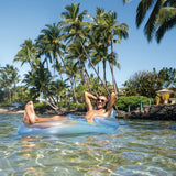This is a lifestyle image showing a man sitting in the inflatable chair, floating on the surface of the ocean.