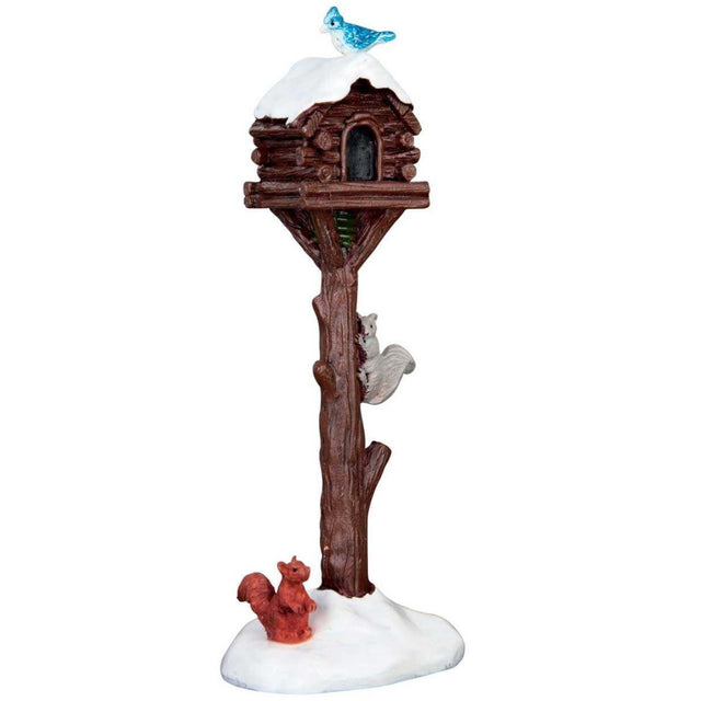 Village accessory for a Lemax display. Designed to look like a wooden birdhouse covered in snow. There's a blue bird on the roof, a gray squirrel climbing up and a brown squirrel standing in the snow at the base.