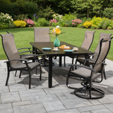 This is a lifestyle image showing this patio dining set on a stone patio in a nice, grassy backyard.