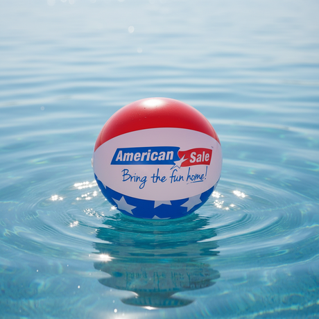 This is a lifestyle image showing a beach ball on top of the water. The beach ball is red, white and blue striped and reads "American Sale. Bring the fun home!"