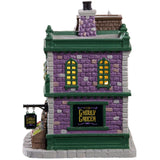 Porcelain lighted building for a Lemax display. Designed to look like a brick grocery store. There are monsters at the front door and boxes of stuff you can buy near the front window. Inside the window, you can see some creepy crawlies hanging from hooks. There are carved pumpkins on the roof.