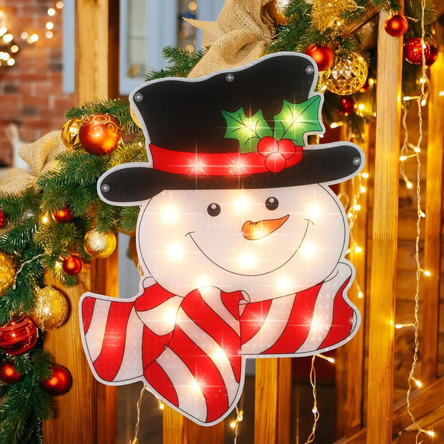 Pre-lit decoration shaped like a smiling snowman wearing a black top hat with holly leaves and berries and a red and white striped scarf.