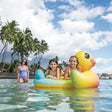 This is a lifestyle image showing two young girls resting on the inflatable duck while a mom looks on.