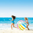 This is a lifestyle image showing two little girls playing with this jumbo ball on the beach.