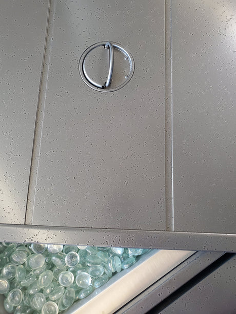 This is an up close view of the lid of this fire pit table. It's partially covering the fire glass inside.