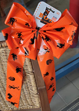 Orange bow with black figures on it. The figures include a skeleton, a pumpkin, a cat, a switch on a broom and a bat.