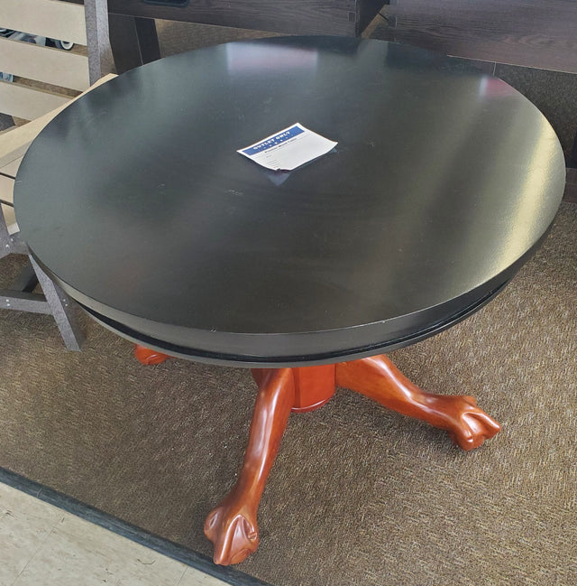 Round, wooden table. Tabletop is black and the legs are a cherry wood color.