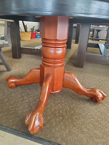 Round, wooden table. Tabletop is black and the legs are a cherry wood color.