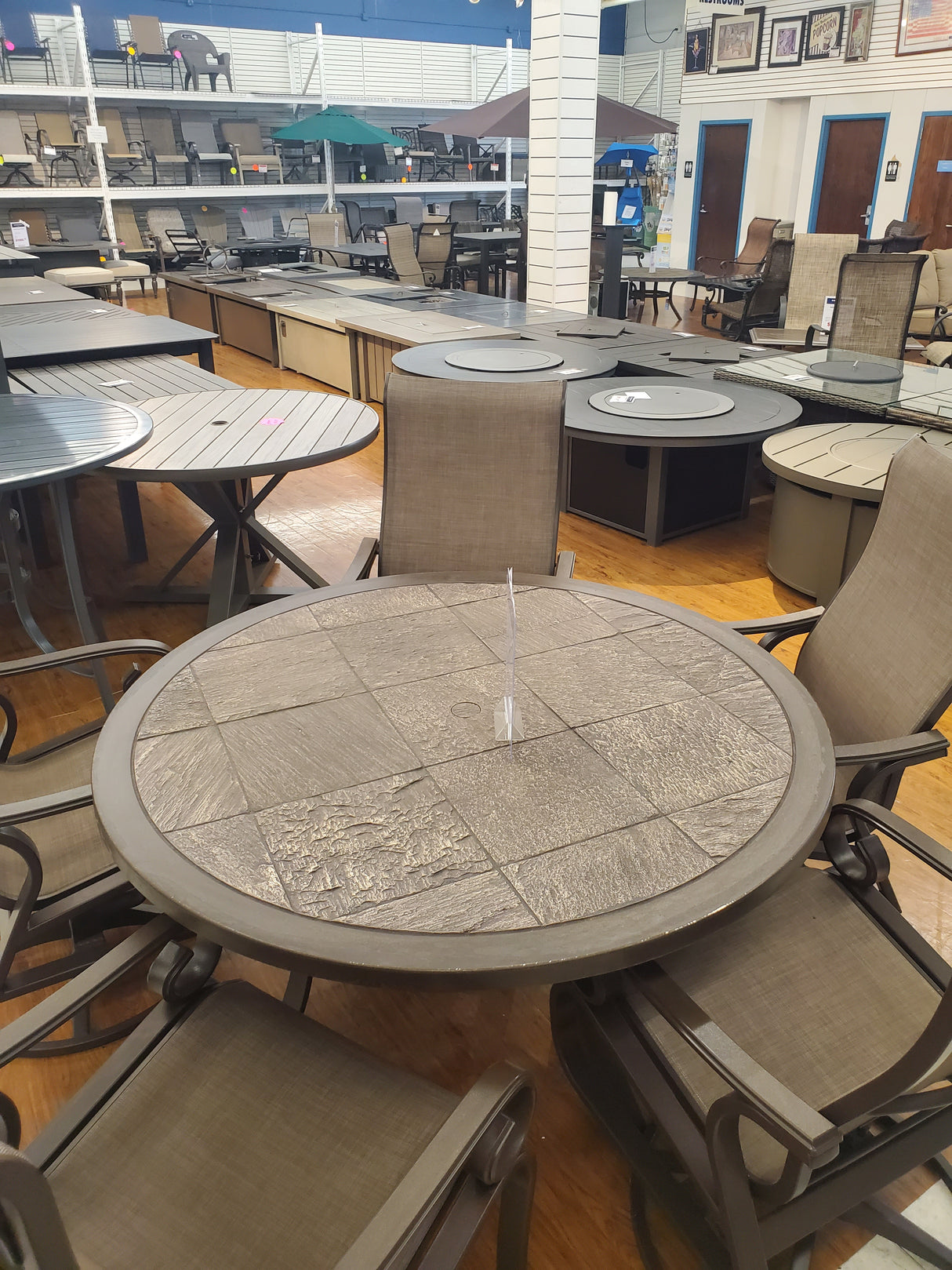 Round outdoor table with chairs displayed in the Outlet store with clearance firepits in the background.