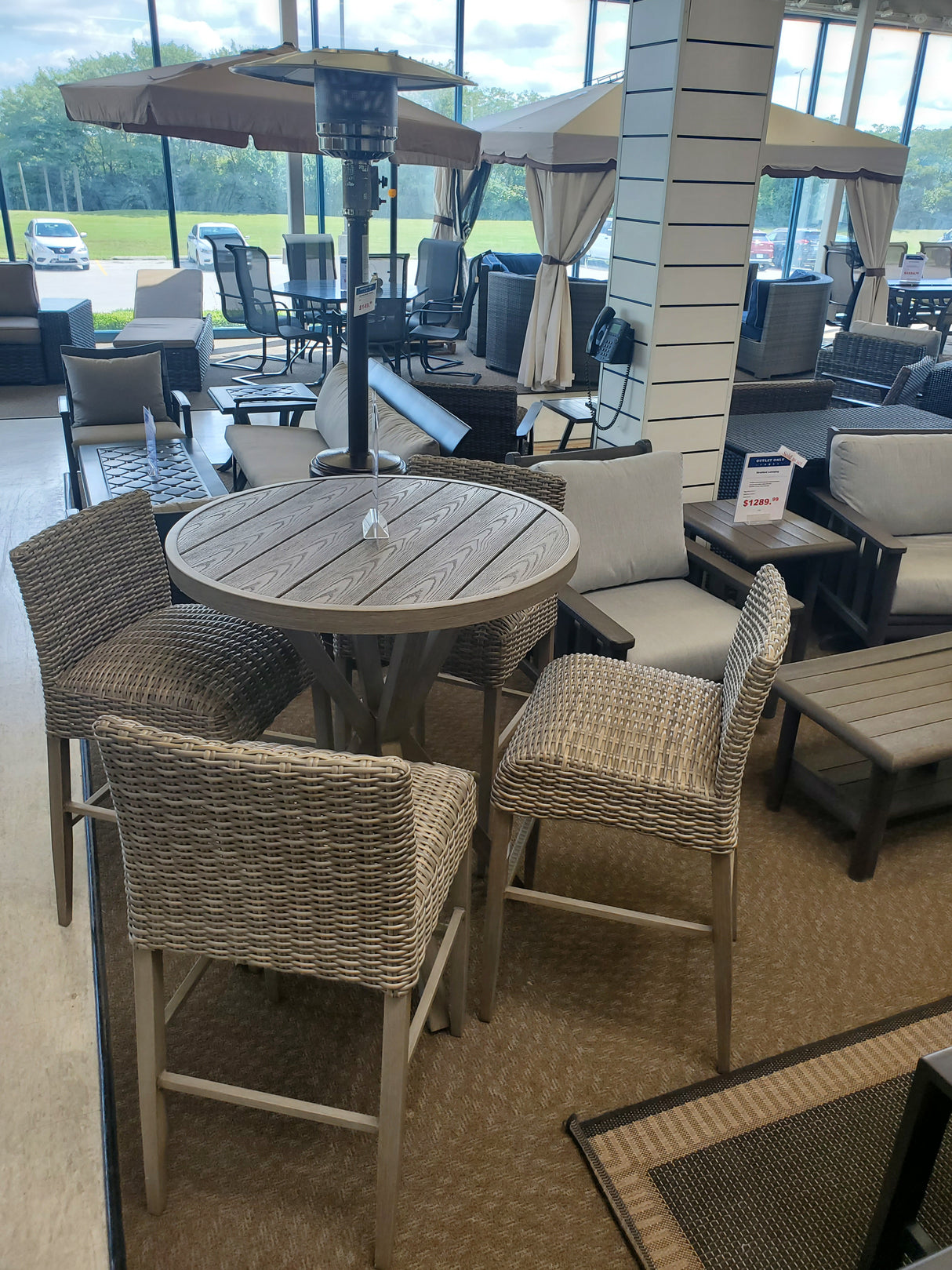 Clearance outdoor bar height patio furniture set with round table and wicker chairs in a the Tinley Park Outlet store.