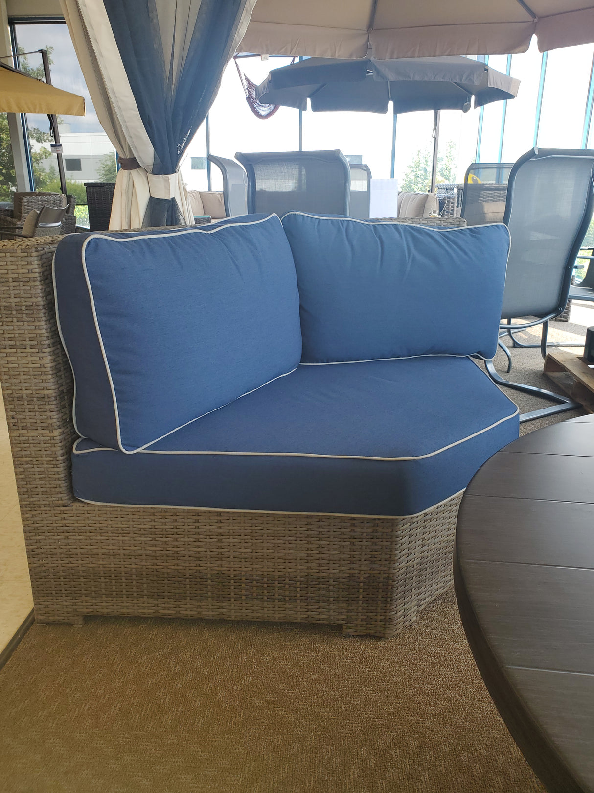Corner wicker outdoor patio chair with blue cushion in the Tinley Park Outlet store.