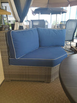 Corner wicker outdoor patio chair with blue cushion in the Tinley Park Outlet store.