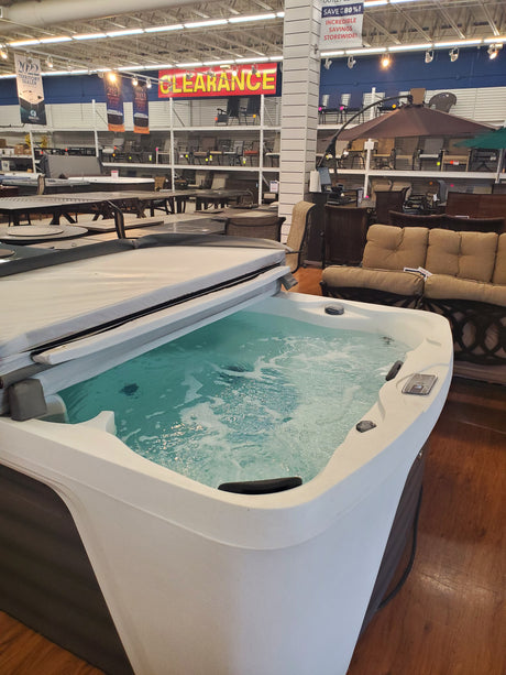 Clearance hot tub filled with water on display in the Tinley Park Outlet with furniture and signs in the background.