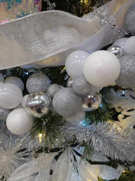 This is a lifestyle image showing this beaded garland wrapped around a tree along with other ribbons, ornaments and tinsel garland.
