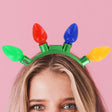 Green headband with four oversized bulbs that light up. One bulb is green, one bulb is red, one bulb is blue and one bulb is yellow.