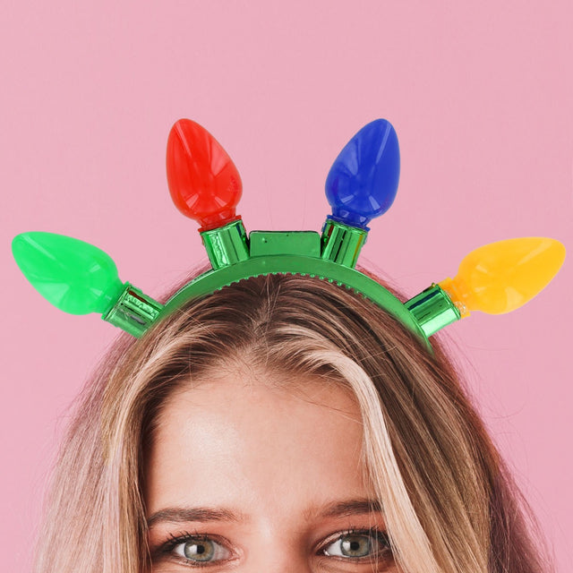 Green headband with four oversized bulbs that light up. One bulb is green, one bulb is red, one bulb is blue and one bulb is yellow.