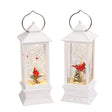 White lantern decoration with glitter and a woodland scene with a cardinal inside.