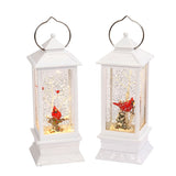 White lantern decoration with glitter and a woodland scene with a cardinal inside.