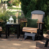 This is the Cedar and Black colored classic glider chair on a stone patio. There's a forest green throw pillow on the seat.