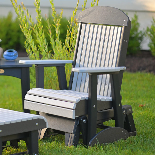 This is a lifestyle image showing the Dove Gray and Black colored classic glider chair in a grassy yard.