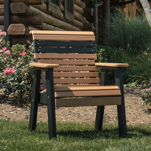 This is a lifestyle image showing the Antique Mahogany and Black colored bench on a grassy patio outside of a log cabin.